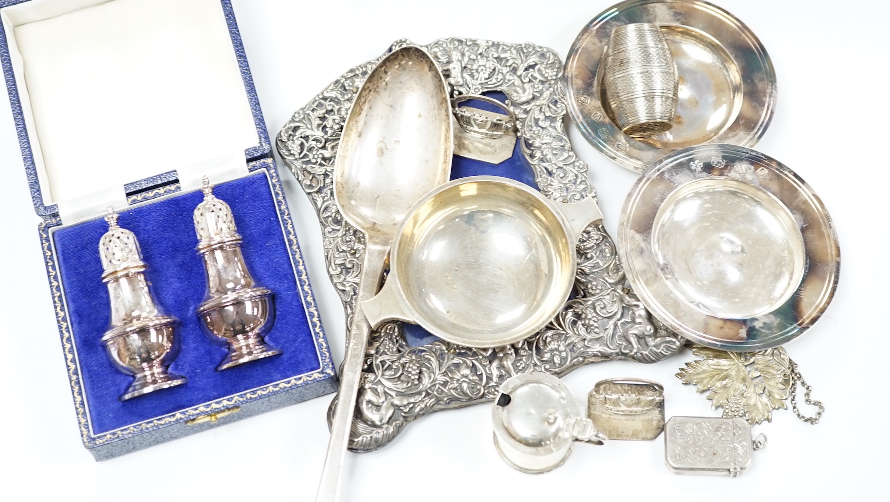 A quantity of silver items including a late Victorian repousse photograph frame, William Comyns, London, 1899, 20cm, three Georgian pepperettes, pair of small Armada dishes, quaich, vest case, menu holder, basting spoons